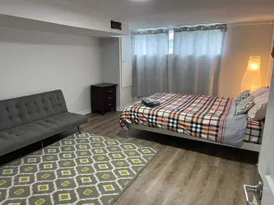 a bedroom with a bed and a couch and a rug at Cozy basement 2 bedroom 2 bath with parking in Richmond Hill