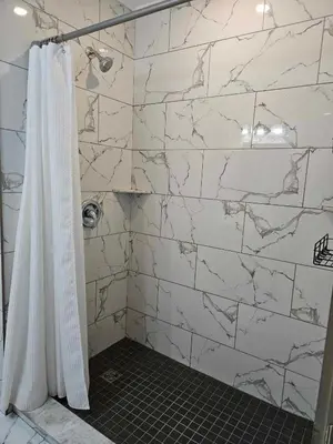 a bathroom with a shower with a white marble wall at France and Flowers - Private 3-Bed Apartment in Stratford