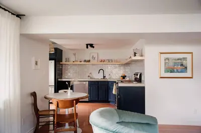 a kitchen with a table and a kitchen with blue cabinets at The Dainty Petunia in Picton