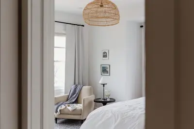 a bedroom with a bed and a chair and a window at The Hull House - Lake Ontario Waterfront w Sauna in Wellington