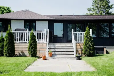 a house with a porch and stairs with plants at Wellers Landing - Prince Edward County Lakehouse in Carrying Place