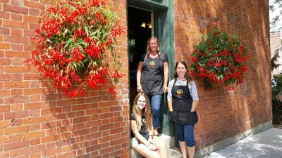 three women standing next to a brick wall with flowers at Greaves Sweet Escape in Niagara on the Lake