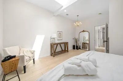 a white bedroom with a large bed and a chair at The Belvedere:Front Street Flats in Belleville