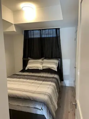 a small bedroom with a bed with a window at Lovely one bedroom condo with free parking in Niagara Falls