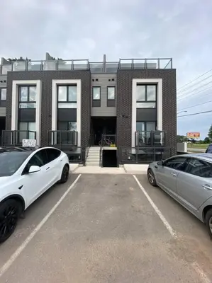 two cars parked in a parking lot in front of a building at Lovely one bedroom condo with free parking in Niagara Falls