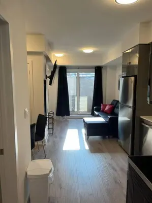 a living room with a couch and a refrigerator at Lovely one bedroom condo with free parking in Niagara Falls