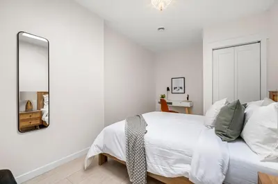 a white bedroom with a bed and a mirror at The Olympia: Front Street Flats in Belleville