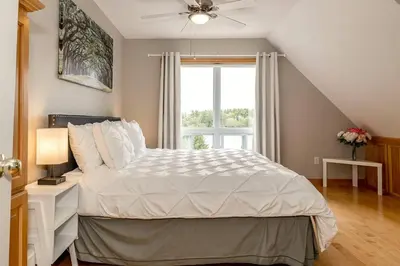 a bedroom with a white bed with a window at Muskoka Lakeshore Cottage Bliss in Gravenhurst