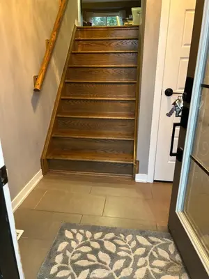 a hallway with stairs with a rug in front of a door at Jahsavvy's Nest in Hamilton