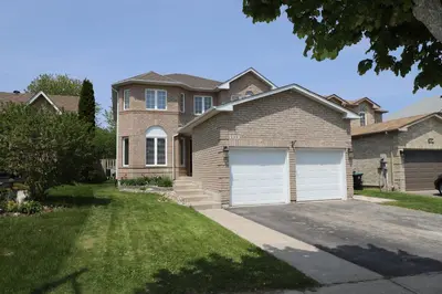 a brown brick house with two white garage doors at Lavish 4BR House Near Simcoe Lake & FH Resort in Innisfil