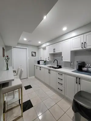 a white kitchen with white cabinets and a sink at RoryHouse in Toronto