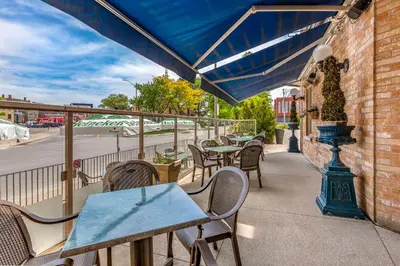 a patio with tables and chairs and a blue umbrella at The Parlour Inn, an Ascend Collection Hotel in Stratford