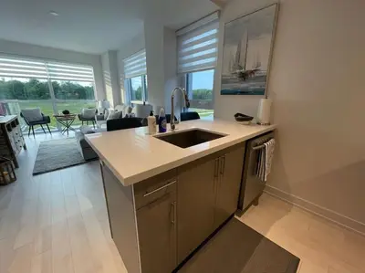 a kitchen with a sink and a living room at 2 bedroom 2 bath Aquarius, Friday Harbour, Innisfil, Barrie in Innisfil