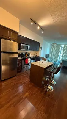 a kitchen with a table and a stainless steel refrigerator at Lakeview Condo in Downtown with Free Parking. in Toronto