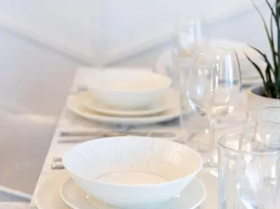 a table with a white bowl and plates and glasses at Pristine Modern 2BR Condo Private BBQ and Balcony in Toronto