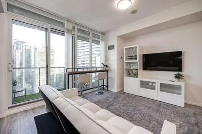 a living room with a white couch and a large window at Cityscape 1BR Condo with Private Balcony amd WFH setup in Toronto