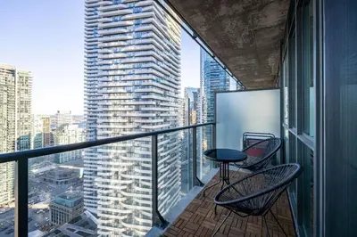 a balcony with two chairs and a table on a building at Cityscape 1BR Condo with Private Balcony amd WFH setup in Toronto