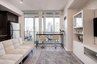 a living room with a white couch and a table at Cityscape 1BR Condo with Private Balcony amd WFH setup in Toronto