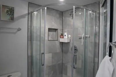 a shower with a glass door in a bathroom at Patio privé, hébergement équipé et spacieux. in Hamilton