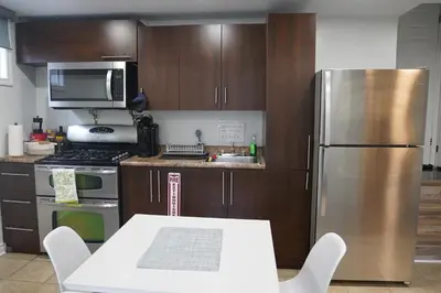 a kitchen with a stainless steel refrigerator and a table at Patio privé, hébergement équipé et spacieux. in Hamilton