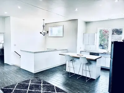 a white kitchen with a counter and stools at Lavida Luxury Room #1 in London in London