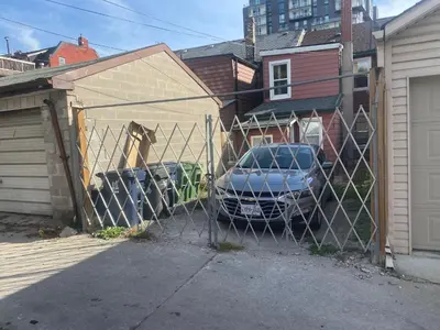 a fence with a car parked in a garage at BUDGET Quad Room with En Suite Bathroom 36B in Toronto
