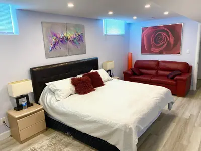 a bedroom with a bed and a red couch at Gilford Beach Apartment in Innisfil