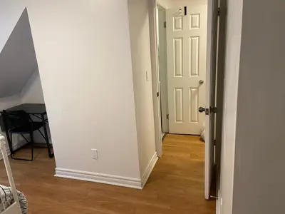 a hallway with a white door and a wooden floor at Quad Room with Private Bathroom 536A-Two Bedrooms in Toronto