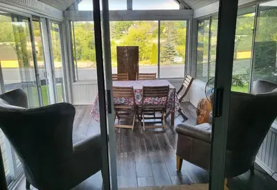 a screened in dining room with a table and chairs at Burnt River Bungalow in Kinmount