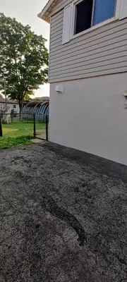 a driveway next to a white house with a window at Lovely apartment house in Grimsby