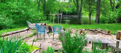 a group of chairs sitting in a garden near a pond at The River Farmhouse in Corbyville