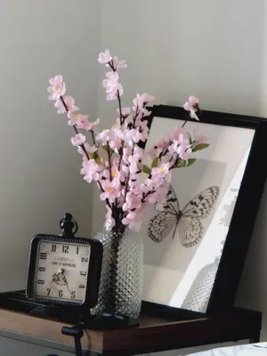 a vase with pink flowers and a clock on a table at 2 Bedroom, 2 Bath Stunning Condo - heart of Kitchener Downtown in Kitchener