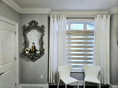 a room with two white chairs and a mirror at Lilen's Home in Toronto