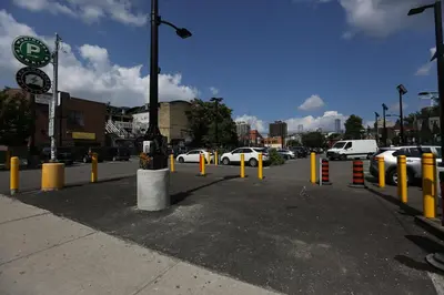 a parking lot with yellow poles and cars on a street at Phoebe Wang in Toronto