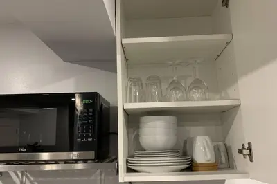 a cupboard with plates and glasses and a microwave at *Cozy, newly renovated, fully equipped* in Hamilton