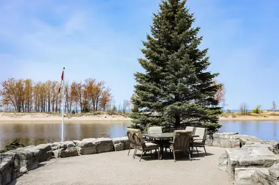 a table and chairs next to a tree and water at The Dockhouse Cottage Five in Wasaga Beach