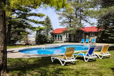 a swimming pool with chairs and a house at The Dockhouse Cottage Five in Wasaga Beach