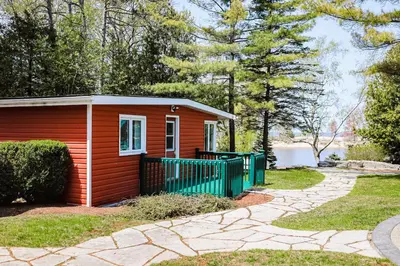 a small red house with a green fence at The Dockhouse Cottage Five in Wasaga Beach