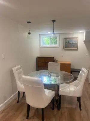 a dining room with a glass table and white chairs at Centre Gate House Licence# 117-2023 in Niagara on the Lake