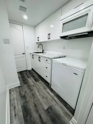 a kitchen with white cabinets and a sink and a microwave at Konia Suites in Orangeville