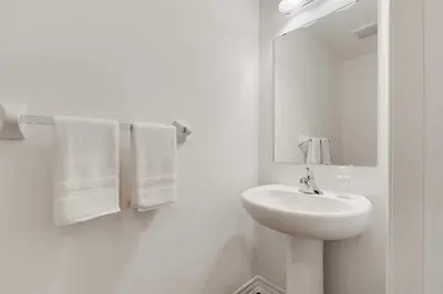 a white bathroom with a sink and a mirror at Konia Suites in Orangeville