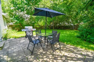 a table and chairs with an umbrella in a backyard at Lake Simcoe 4 Bedroom Family Home Ideal Toronto Area Retreat in Innisfil
