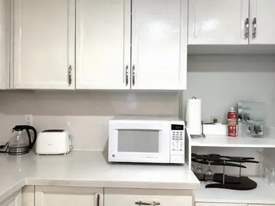 a kitchen with white cabinets and a microwave on a counter at Lake Simcoe 4 Bedroom Family Home Ideal Toronto Area Retreat in Innisfil