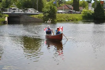 two people are rowing a boat on a river at Balsam Lake Cottage 5 Bed room in Kawartha Lakes