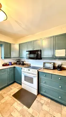 a kitchen with blue cabinets and a white stove top oven at Two bedrooms unit with jacuzzi and great view in Niagara Falls