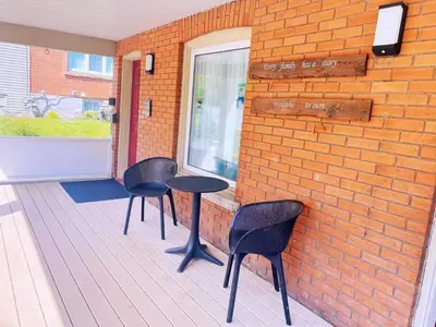 a porch with three chairs and a table and a window at Adorable 2-bedroom unit with jacuzzi beside falls in Niagara Falls