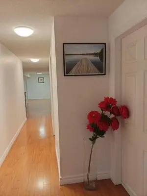 a hallway with a vase with red flowers in it at spacious and bright house in Toronto