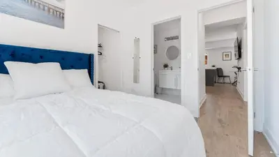 a white bed with a blue headboard in a bedroom at Entire Luxury Suite 4Mins To Falls, Free Parking in Niagara Falls