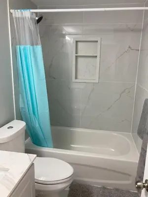 a bathroom with a white toilet and a shower curtain at Brand New, cozy 2 Bdrm Bsmnt Apt in Mississauga
