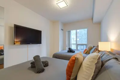 a bedroom with two beds and a flat screen tv at LUX 2BR 1BA Steps to CN Tower W Parking included in Toronto